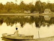 Woman sitting in row boat on Lake Keystone, faced away from camera looking at the view of  homes along the lake shore