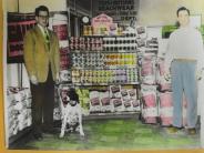 Two men and a dog pose in store in front display of "Watson's Dog Food"